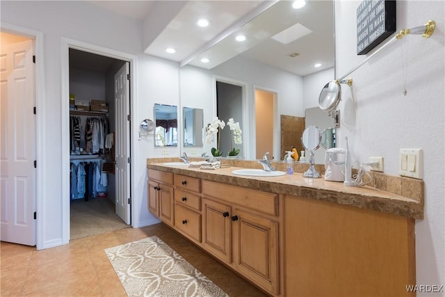 bathroom featuring double vanity, a spacious closet, a sink, and recessed lighting