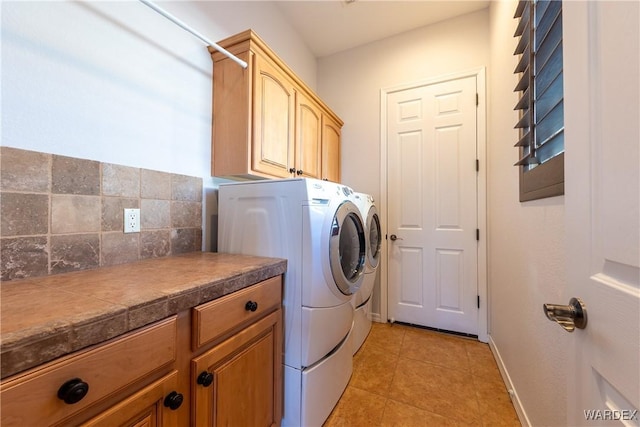 laundry room with baseboards, cabinet space, washing machine and clothes dryer, and light tile patterned floors