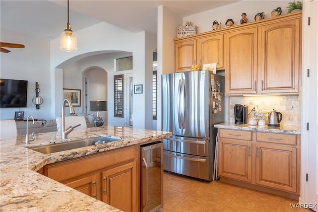 kitchen with tasteful backsplash, decorative light fixtures, light stone countertops, stainless steel appliances, and a sink