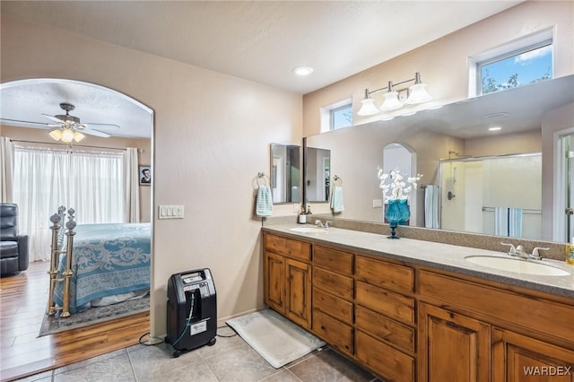 full bathroom with double vanity, a shower stall, connected bathroom, and a sink