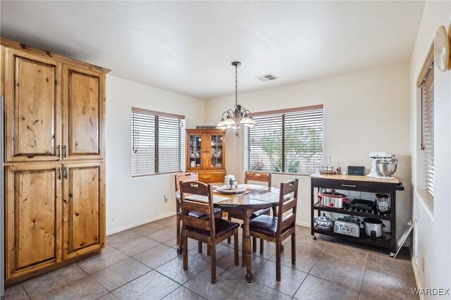 tiled dining area with baseboards, visible vents, a chandelier, and a healthy amount of sunlight