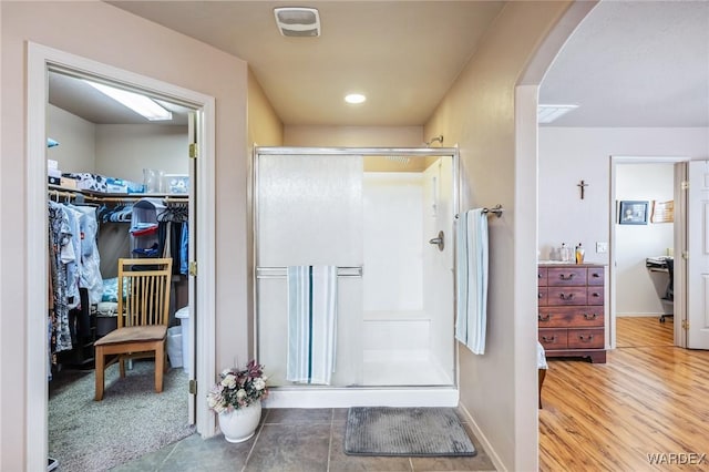 bathroom featuring a shower stall, baseboards, and a walk in closet