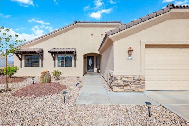 view of front of home featuring a tile roof, an attached garage, stone siding, and stucco siding