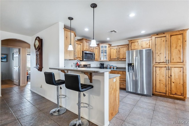 kitchen with visible vents, arched walkways, a peninsula, glass insert cabinets, and appliances with stainless steel finishes