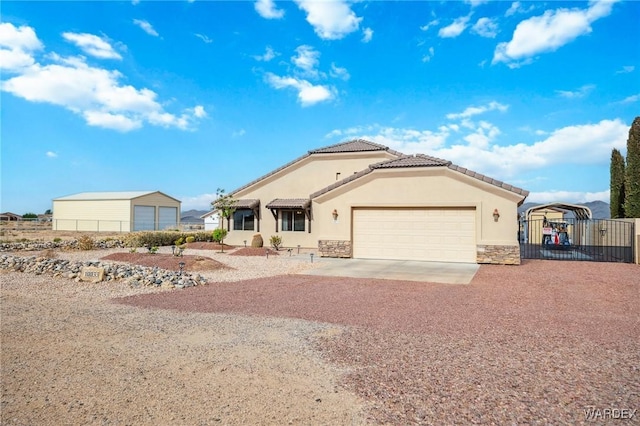 view of front facade featuring a gate, driveway, stone siding, fence, and stucco siding