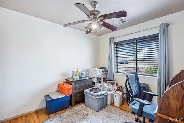 office space with a ceiling fan, wood finished floors, and visible vents