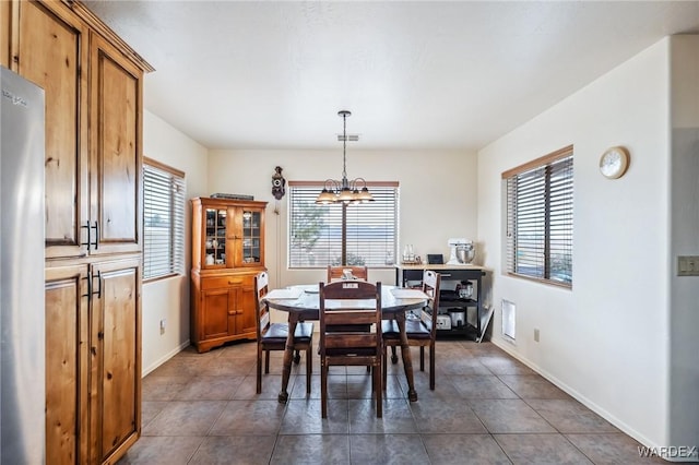 dining area with dark tile patterned floors, plenty of natural light, visible vents, and an inviting chandelier