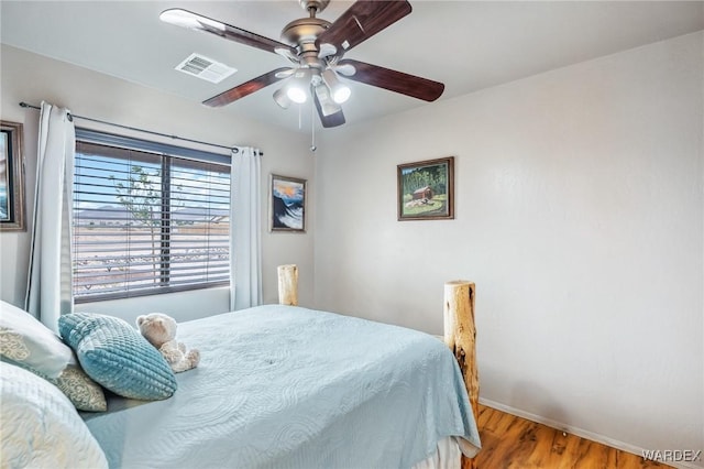bedroom featuring baseboards, wood finished floors, visible vents, and a ceiling fan