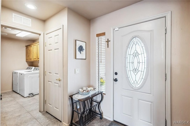 entrance foyer with a wealth of natural light, washing machine and clothes dryer, visible vents, and light tile patterned floors