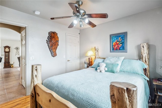 tiled bedroom with arched walkways and ceiling fan