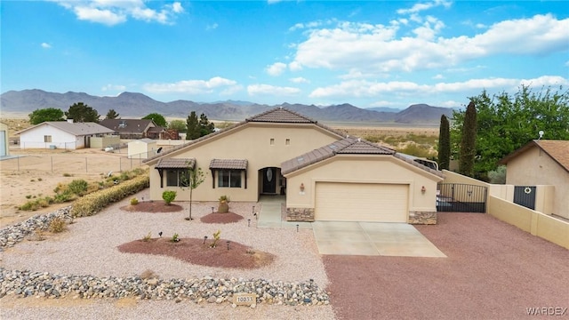 view of front of home with a gate, driveway, an attached garage, a mountain view, and fence