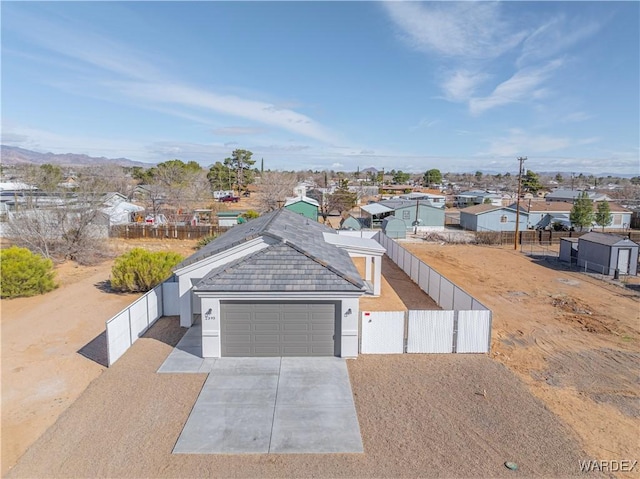 view of front of property with a residential view, stucco siding, a garage, fence private yard, and driveway