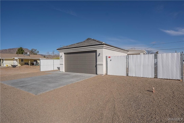 garage with a gate, fence, and concrete driveway