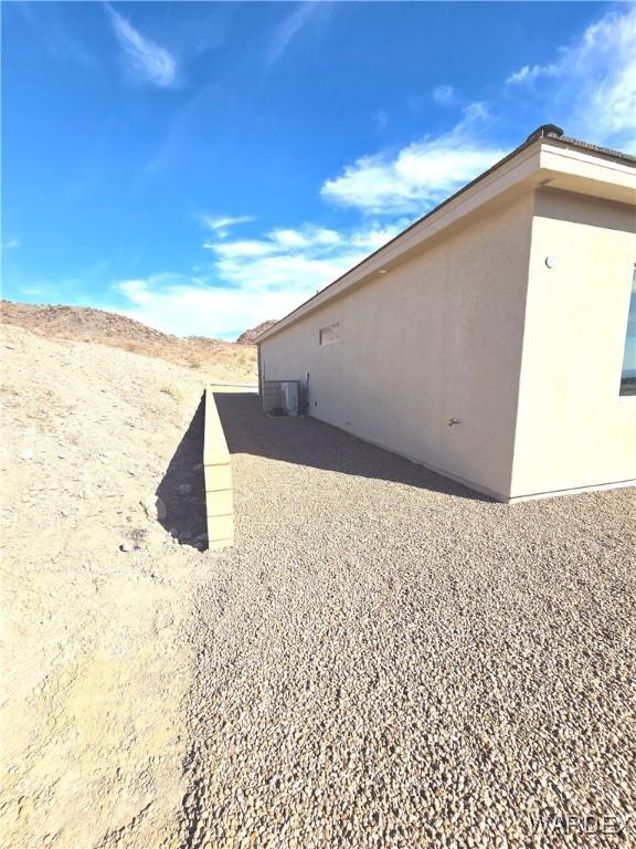 view of side of home with central AC unit and stucco siding