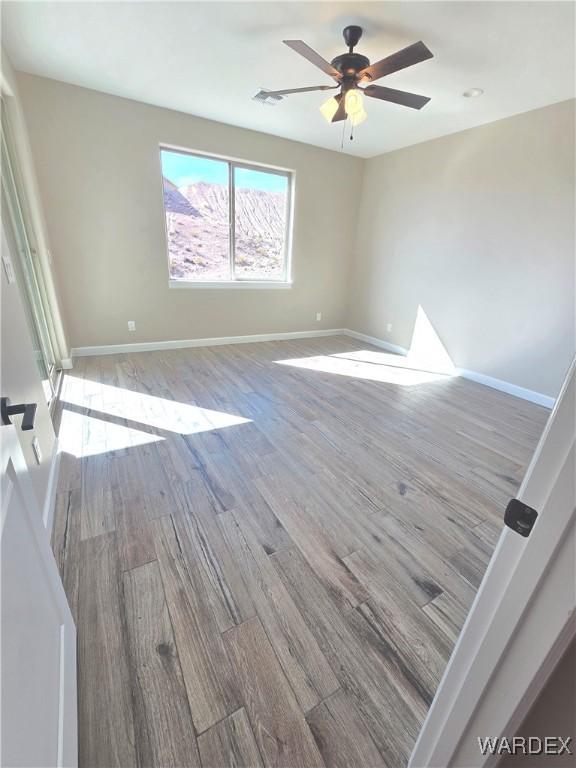 unfurnished room featuring light wood-style floors, visible vents, ceiling fan, and baseboards