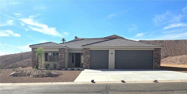 view of front facade with a garage, a tile roof, driveway, stone siding, and stucco siding