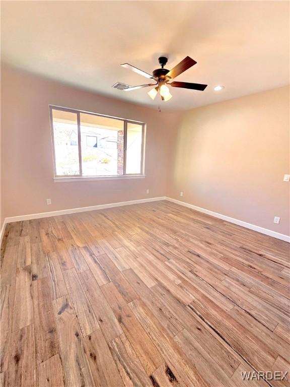 spare room featuring ceiling fan, light wood finished floors, visible vents, and baseboards