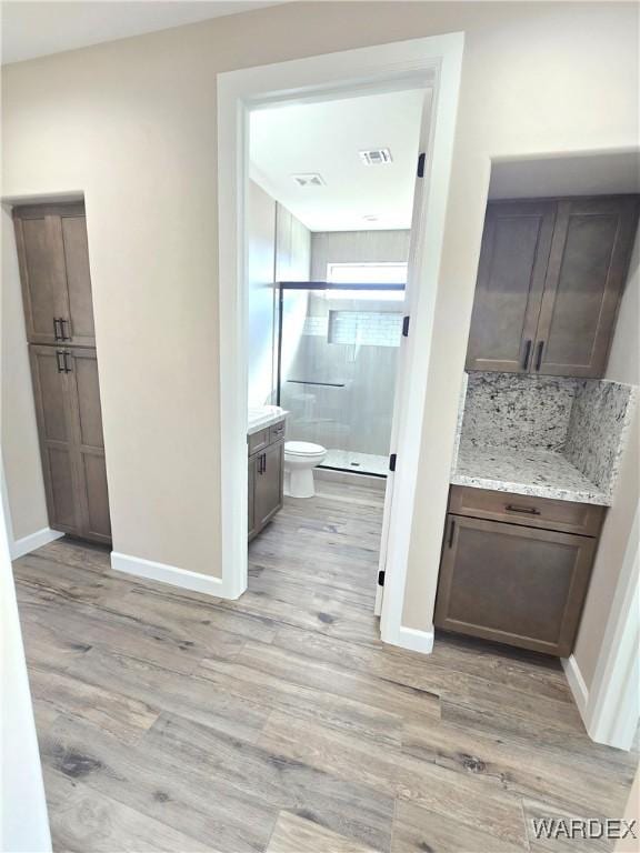 full bath featuring baseboards, toilet, wood finished floors, vanity, and a shower stall