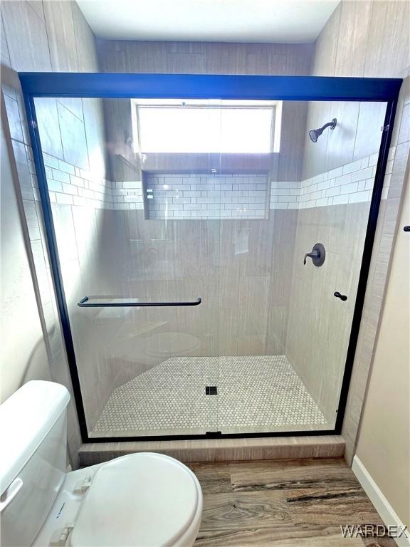 full bathroom with a shower stall, toilet, and wood finished floors