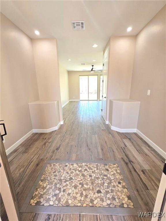 hallway with recessed lighting, visible vents, baseboards, and wood finished floors