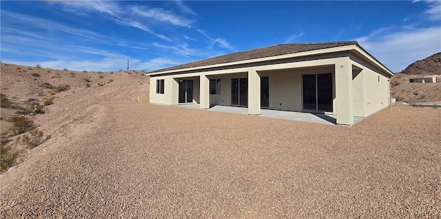 back of property featuring a patio area, a mountain view, and stucco siding