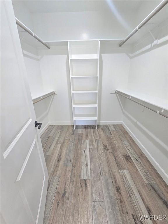 walk in closet with wood finished floors