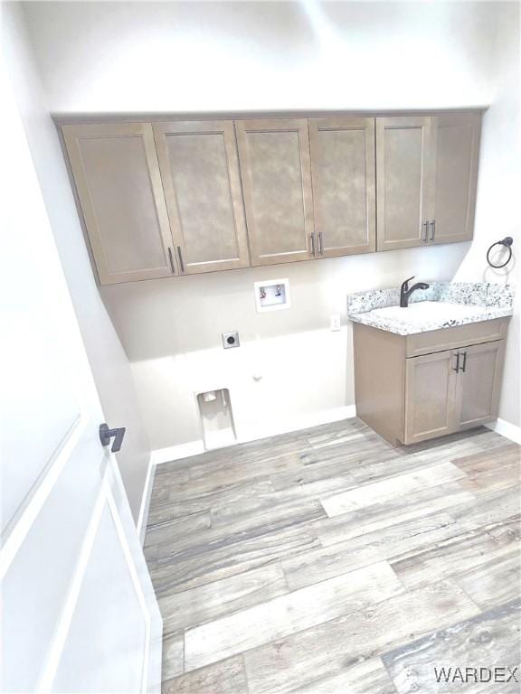 washroom featuring a sink, hookup for a washing machine, light wood-style floors, and cabinet space