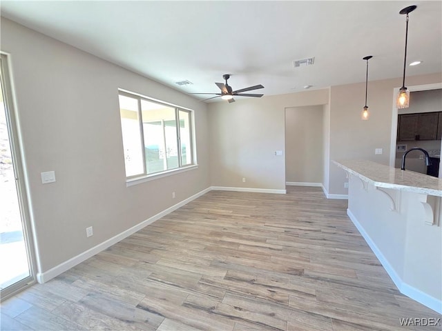 unfurnished living room with light wood finished floors, visible vents, and a sink