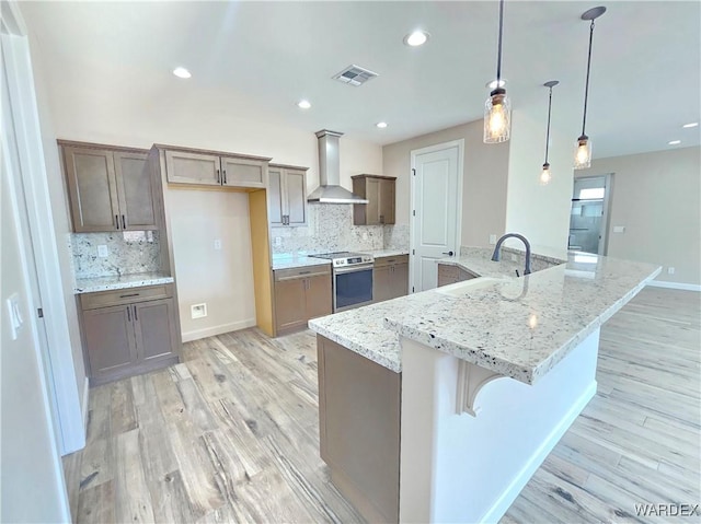 kitchen with a spacious island, visible vents, hanging light fixtures, wall chimney range hood, and stainless steel range with electric stovetop