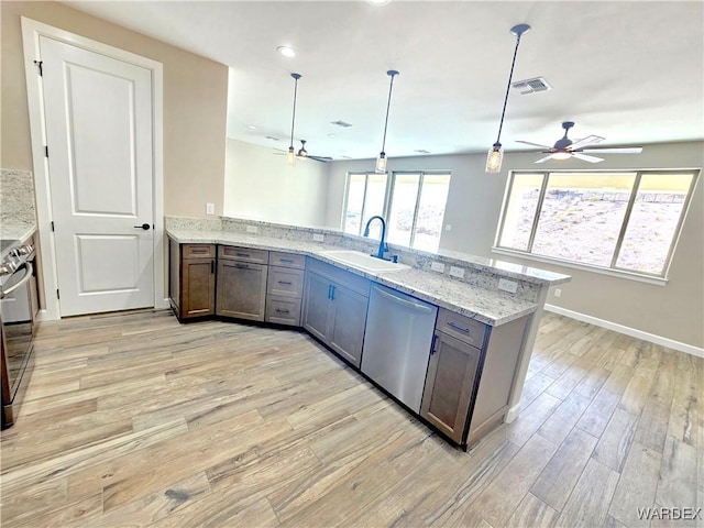 kitchen with visible vents, appliances with stainless steel finishes, light stone counters, pendant lighting, and a sink