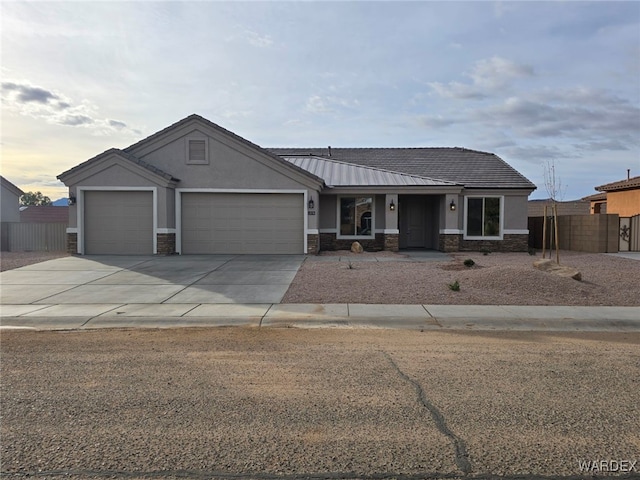 view of front of property featuring concrete driveway, stone siding, metal roof, an attached garage, and stucco siding