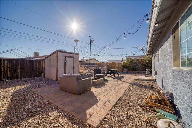 view of patio featuring a storage unit, an outdoor fire pit, an outdoor structure, and a fenced backyard