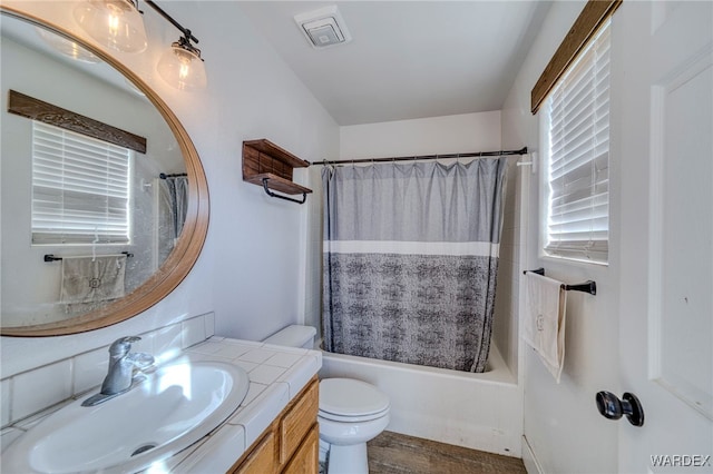 bathroom with visible vents, toilet, wood finished floors, shower / tub combo with curtain, and vanity