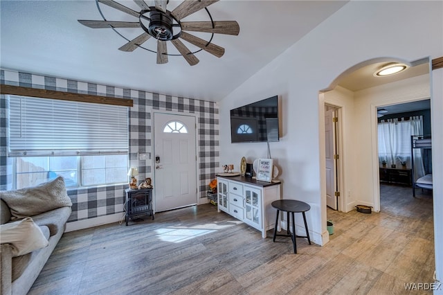 entrance foyer with wallpapered walls, a ceiling fan, vaulted ceiling, and wood finished floors