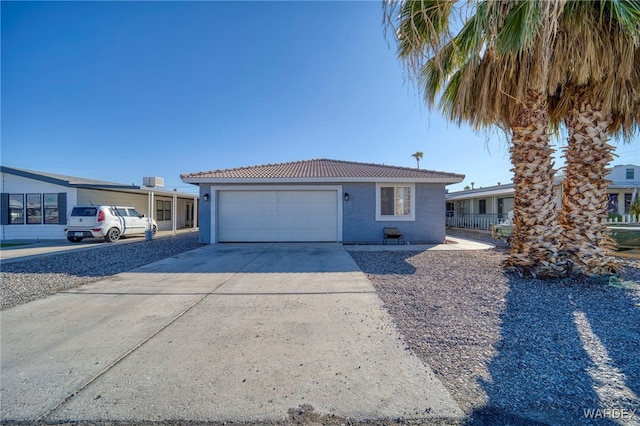 view of front of property featuring driveway, an attached garage, a tiled roof, and stucco siding