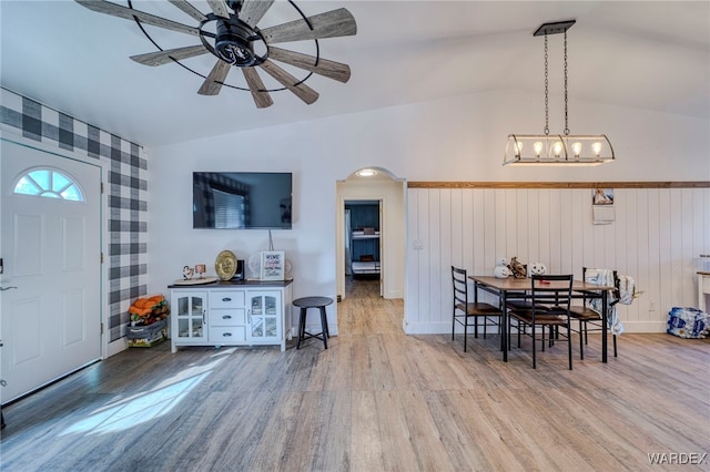 dining area featuring baseboards, arched walkways, a ceiling fan, wood finished floors, and vaulted ceiling