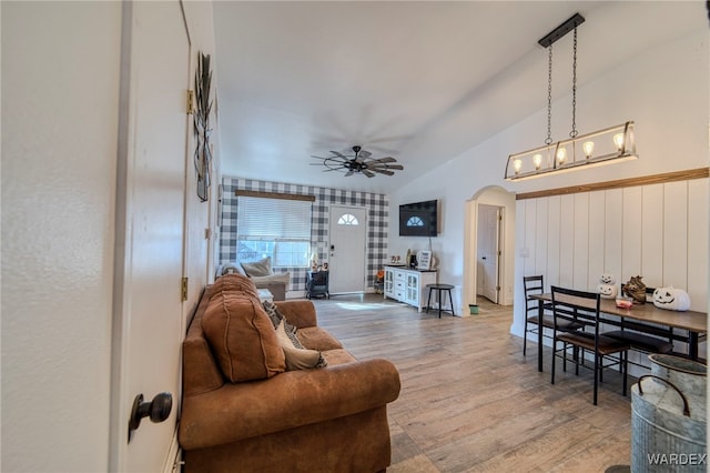 living room featuring lofted ceiling, a ceiling fan, arched walkways, and wood finished floors