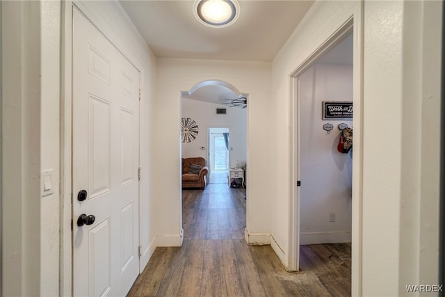 hall featuring visible vents, baseboards, and wood finished floors