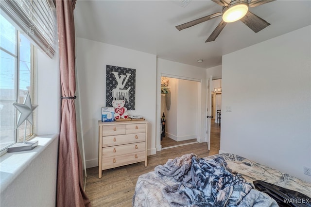 bedroom with light wood-style floors, baseboards, and a ceiling fan