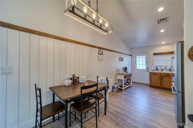 dining room featuring lofted ceiling, recessed lighting, visible vents, wainscoting, and wood finished floors