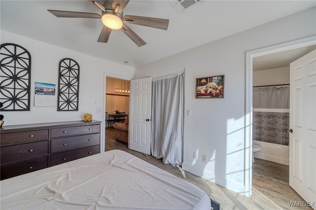 bedroom with light wood-type flooring, connected bathroom, visible vents, and a ceiling fan