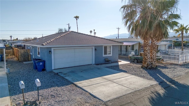 ranch-style home featuring driveway, an attached garage, fence, and stucco siding