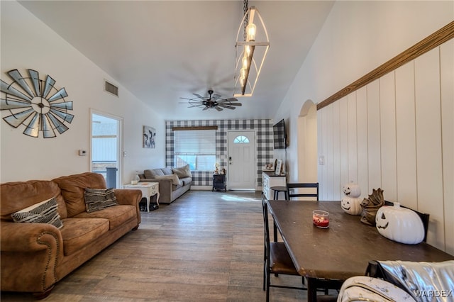 living area featuring dark wood-style floors, visible vents, arched walkways, and ceiling fan