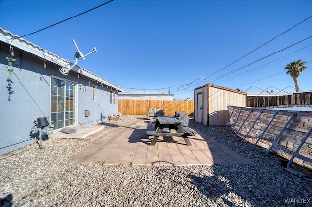 view of yard featuring a shed, a patio, a fenced backyard, and an outbuilding