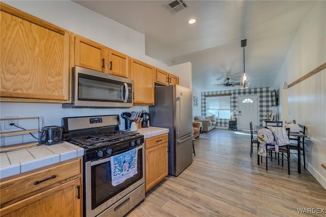 kitchen featuring decorative light fixtures, light wood finished floors, tile counters, visible vents, and appliances with stainless steel finishes