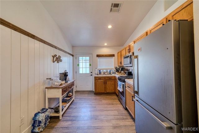 kitchen featuring light countertops, visible vents, appliances with stainless steel finishes, vaulted ceiling, and wood finished floors