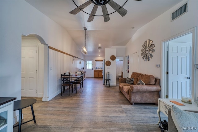 living area with arched walkways, dark wood finished floors, lofted ceiling, visible vents, and ceiling fan