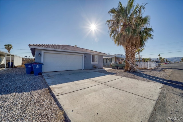 ranch-style home featuring driveway, an attached garage, a tile roof, and stucco siding