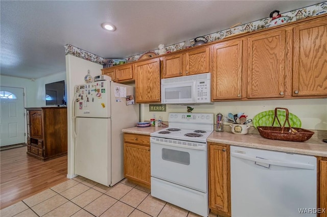 kitchen featuring light countertops, white appliances, and brown cabinetry