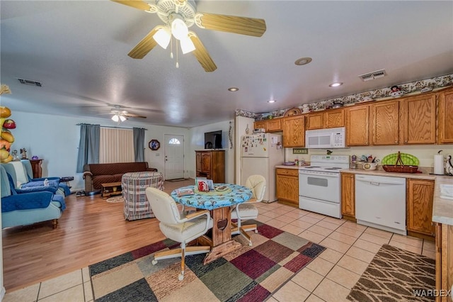 kitchen featuring light countertops, white appliances, visible vents, and brown cabinets